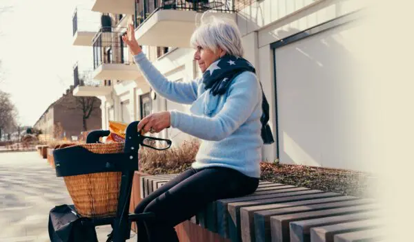 Senior buiten op een bankje met rollator met boodschappen